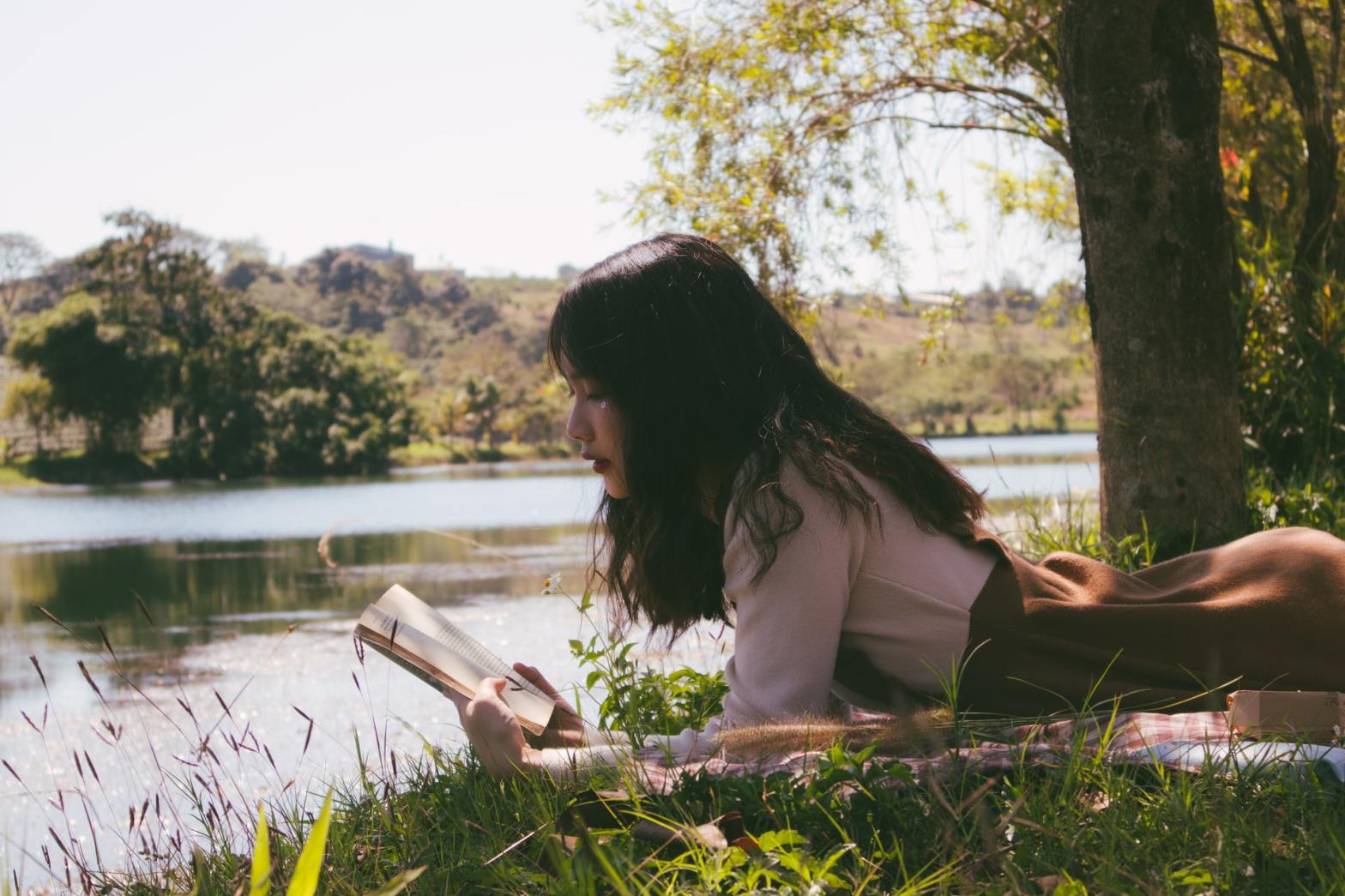 A girl reading a book by the river