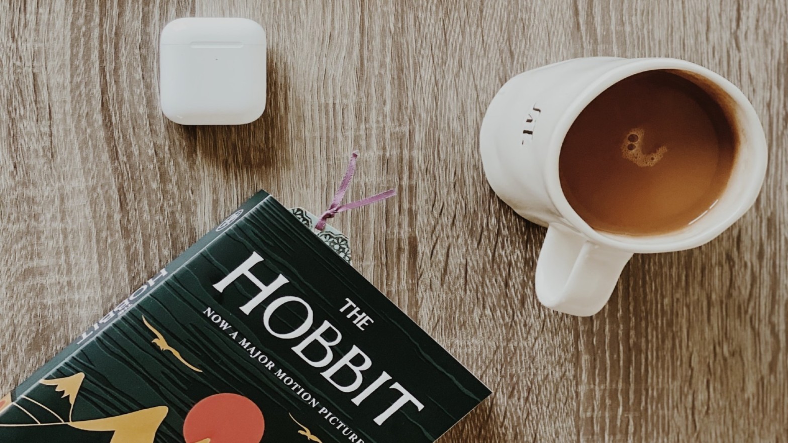 A book, cup of coffee, and airpods