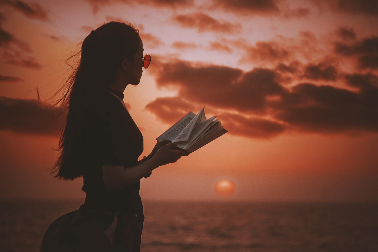 A girl by the sea holding a book